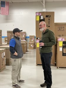 two men talking in hvac warehouse with Trane furnaces and air conditioners in the background