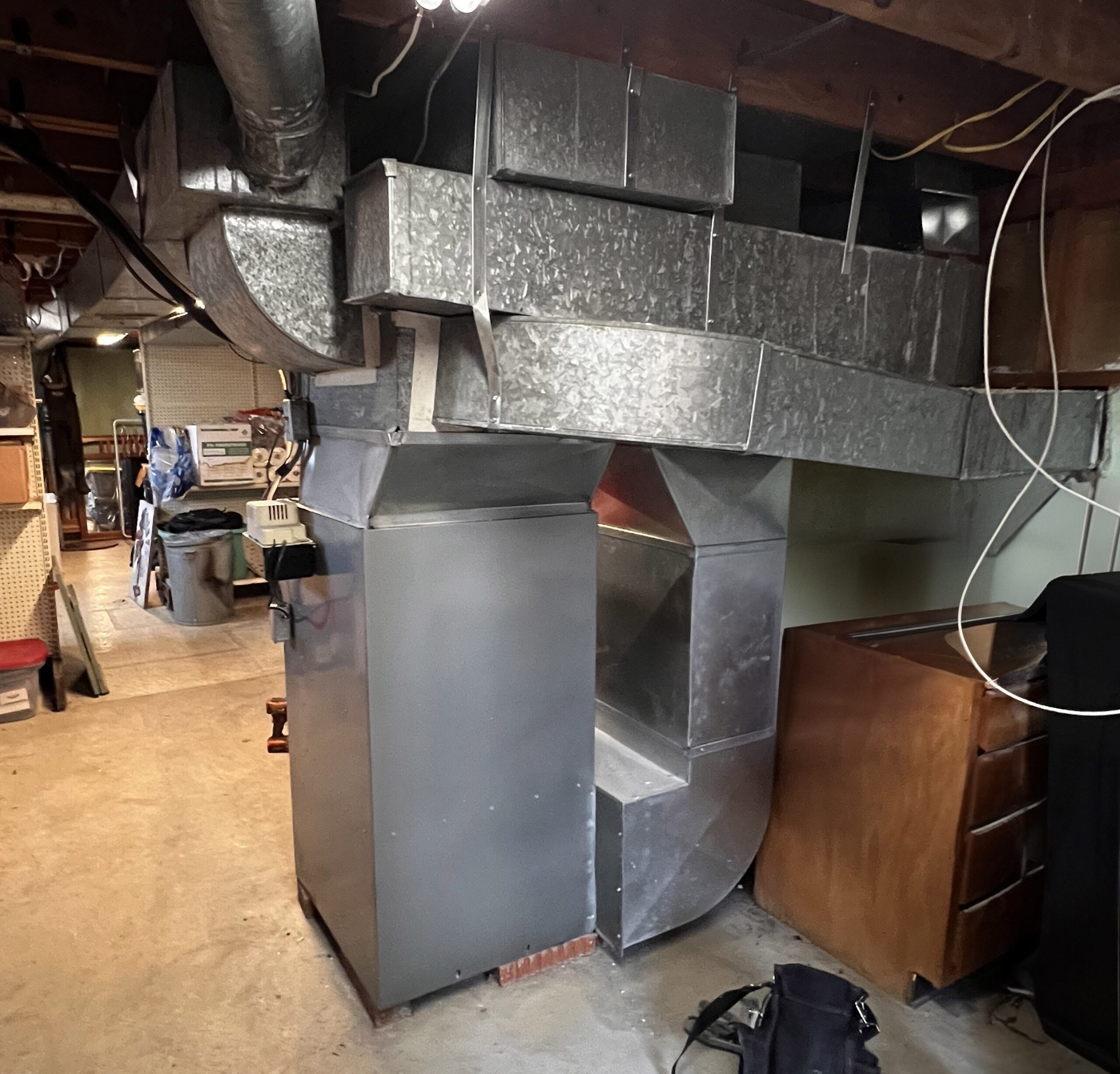 Before picture of an old furnace system with messed up ductwork in Dayton basement