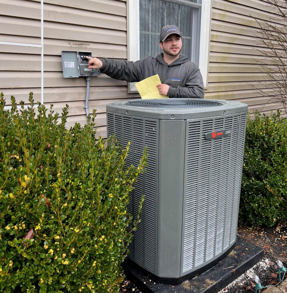 Watkins HVAC tech explains new installed Trane air conditioning unit to customer outside